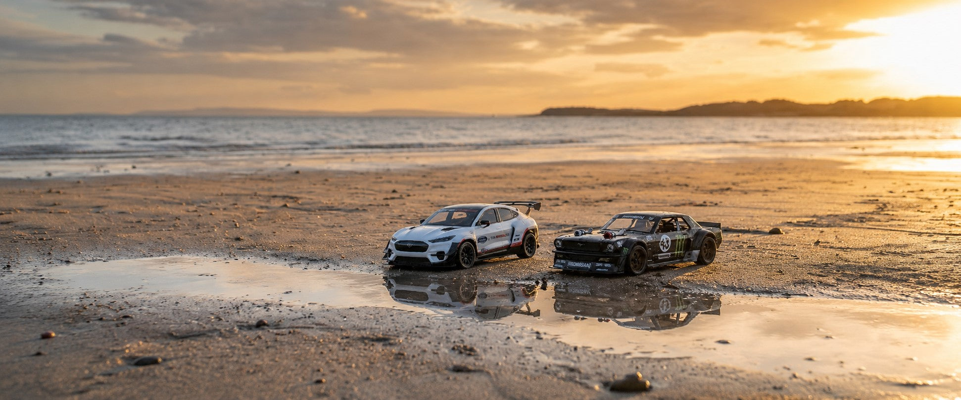 Two cars on a beach at sunset with ocean in the background