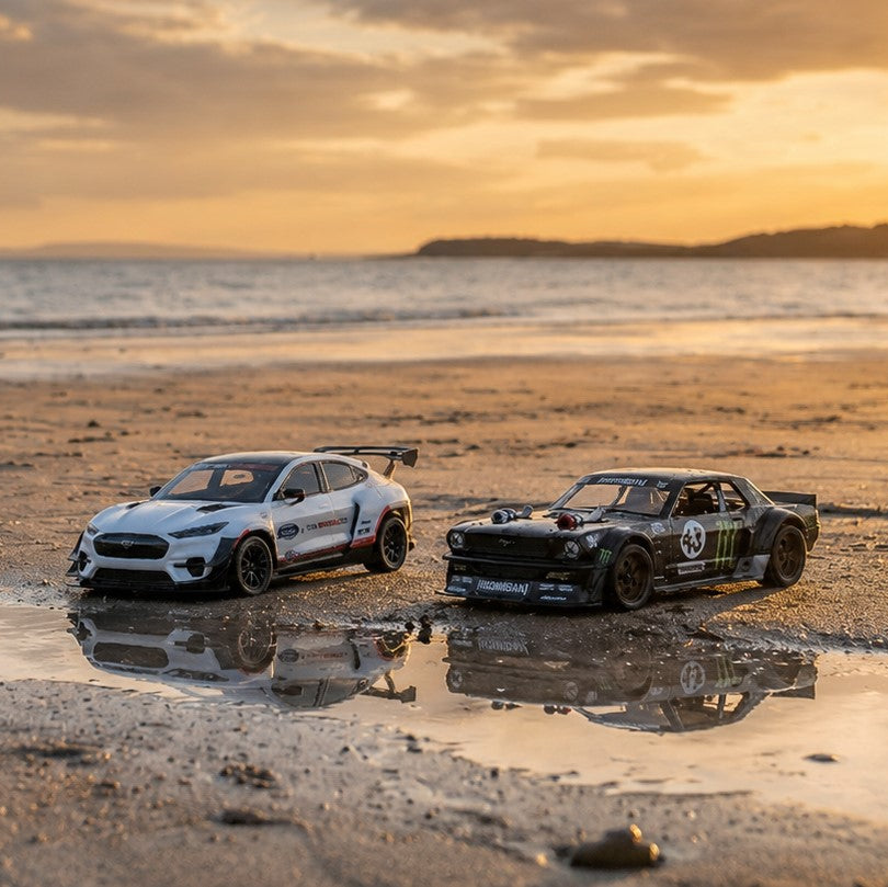 Two model cars on a beach with a sunset in the background